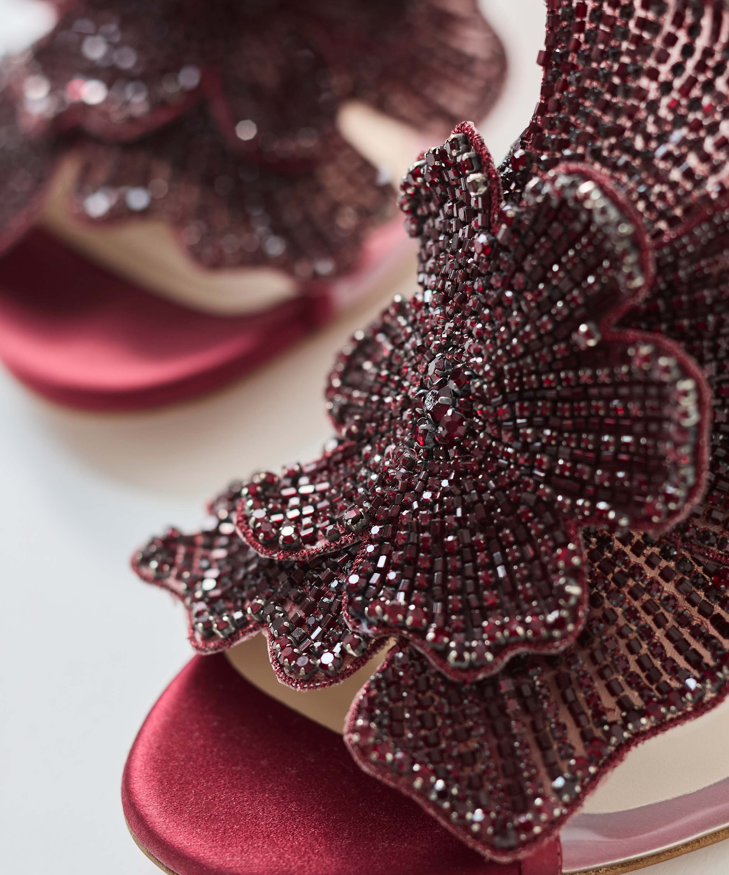 Close-up of a burgundy mule with floral embellishments on a light background