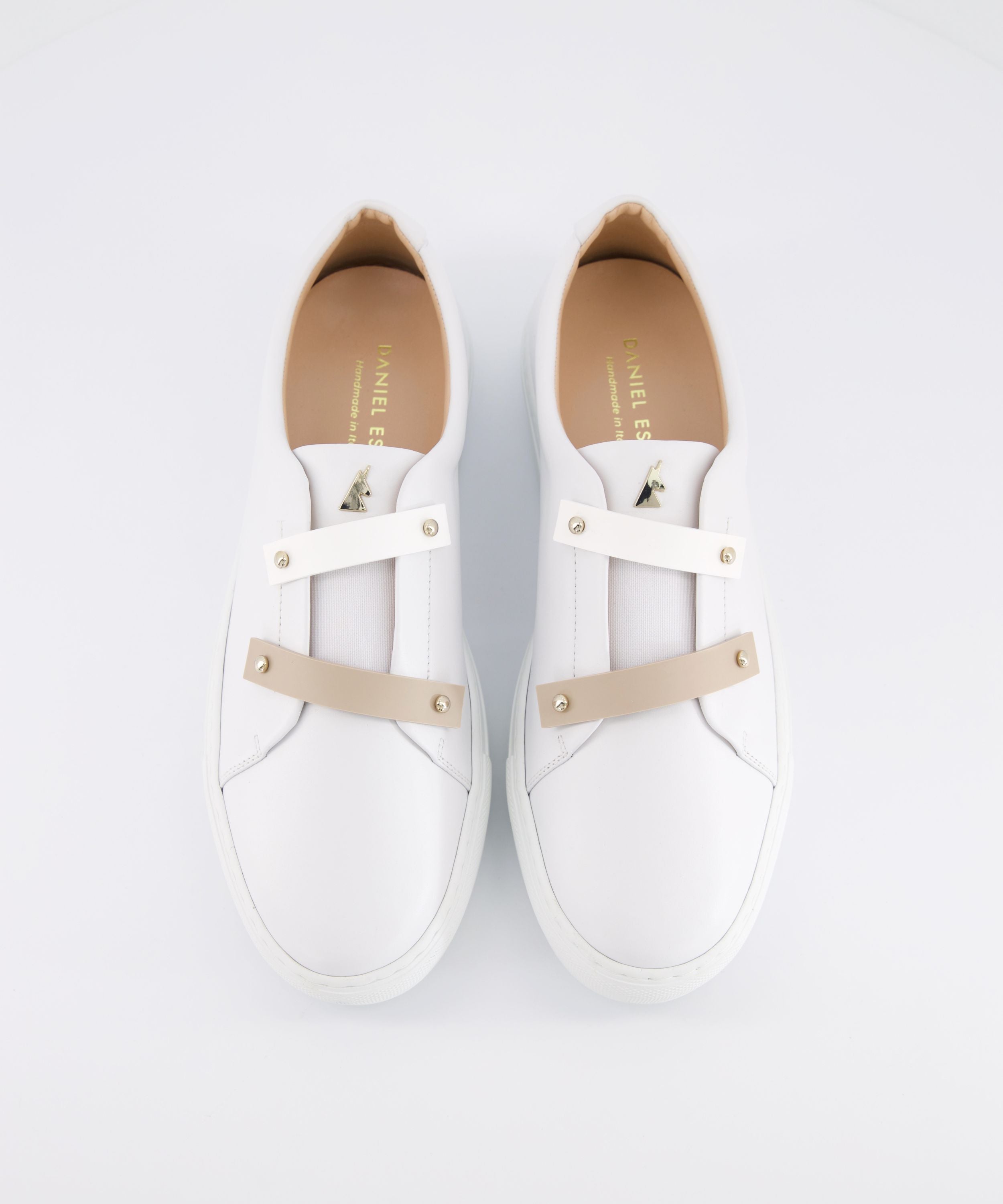 Top-down view of white leather Nous women sneakers, showcasing customizable white and beige strap detailing and gold-tone hardware, set against a clean white background
