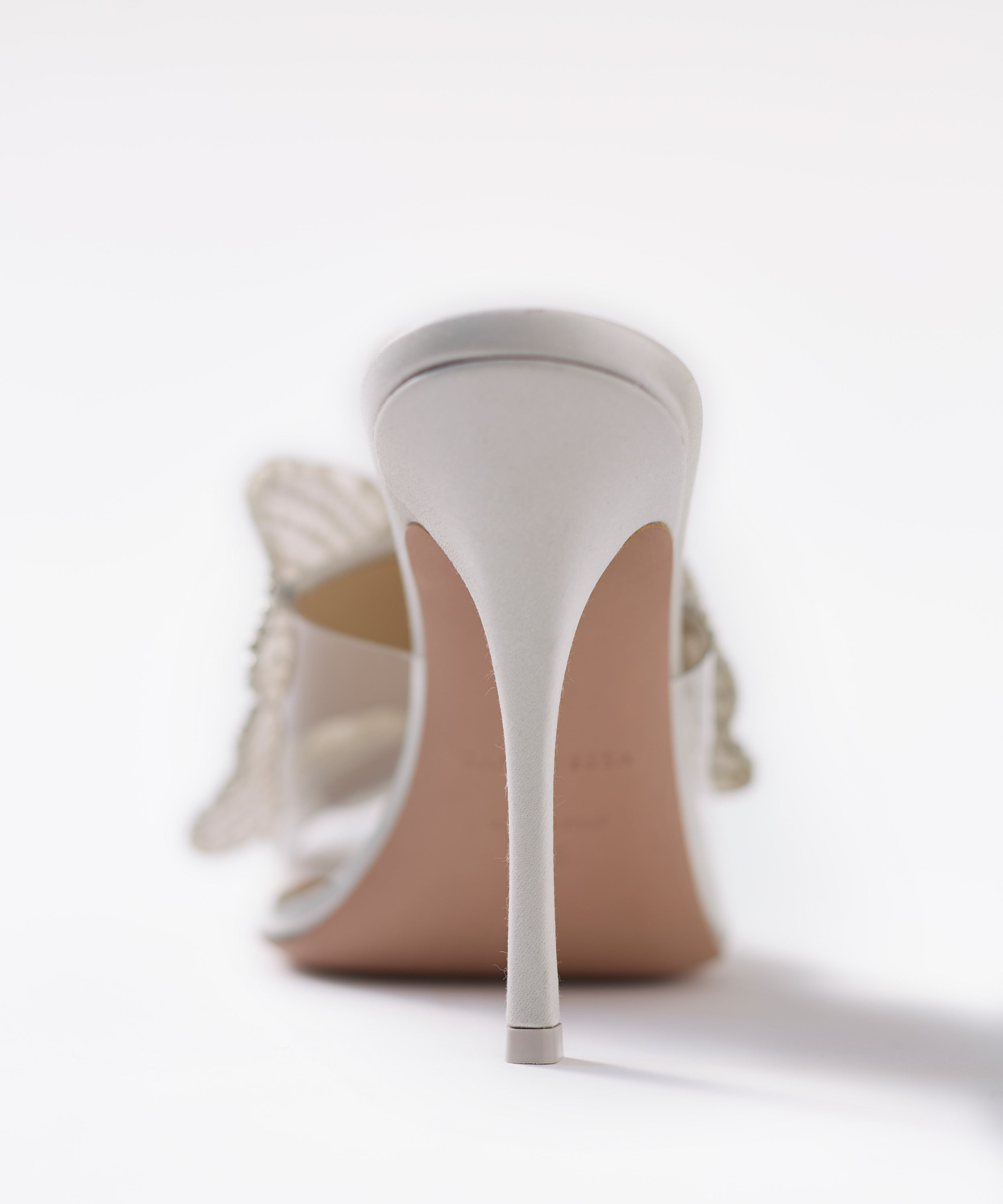 Silver high-heeled shoes with a thin satin heel on a white background