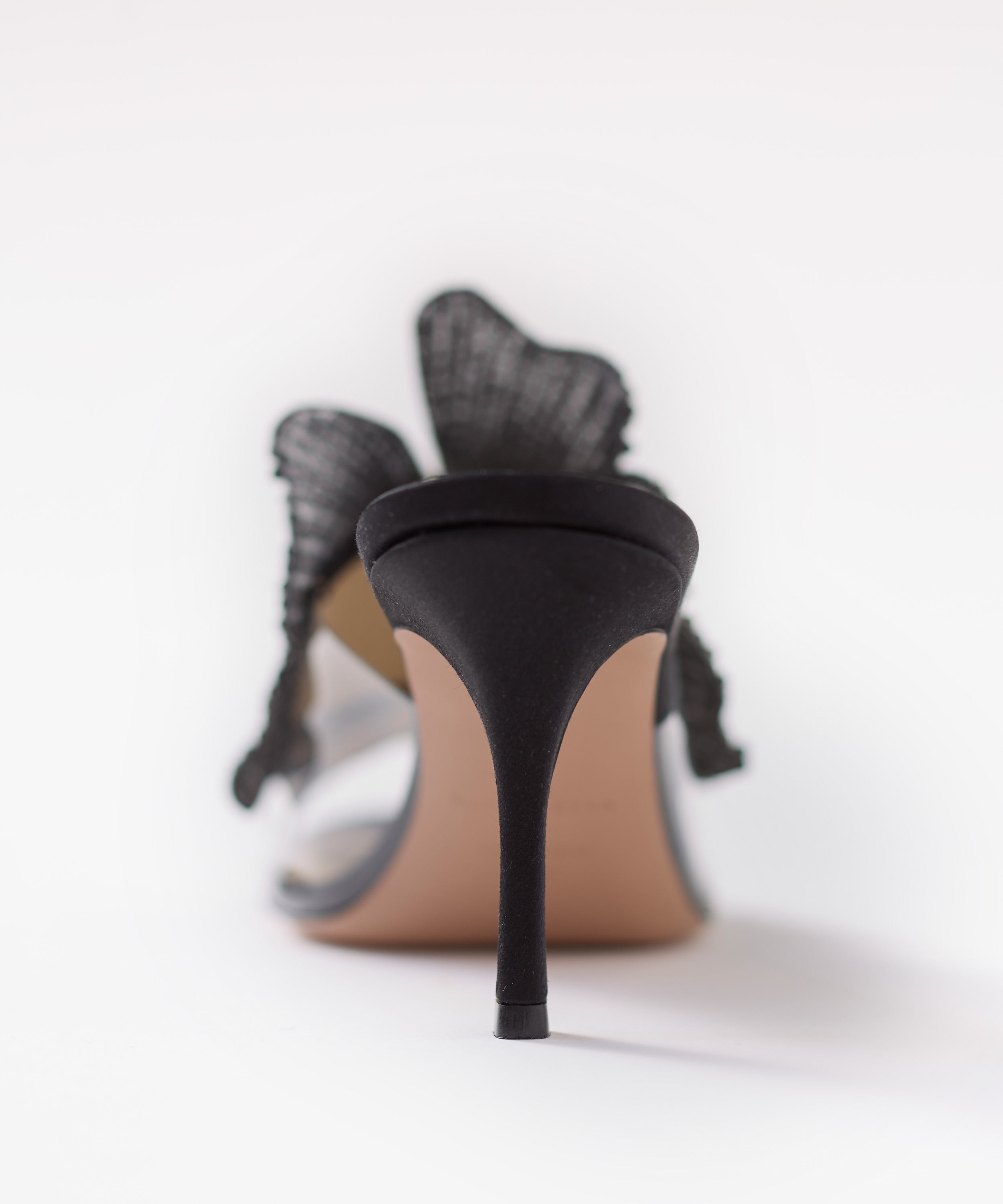 Black satin high-heeled shoes with flowers on a white background
