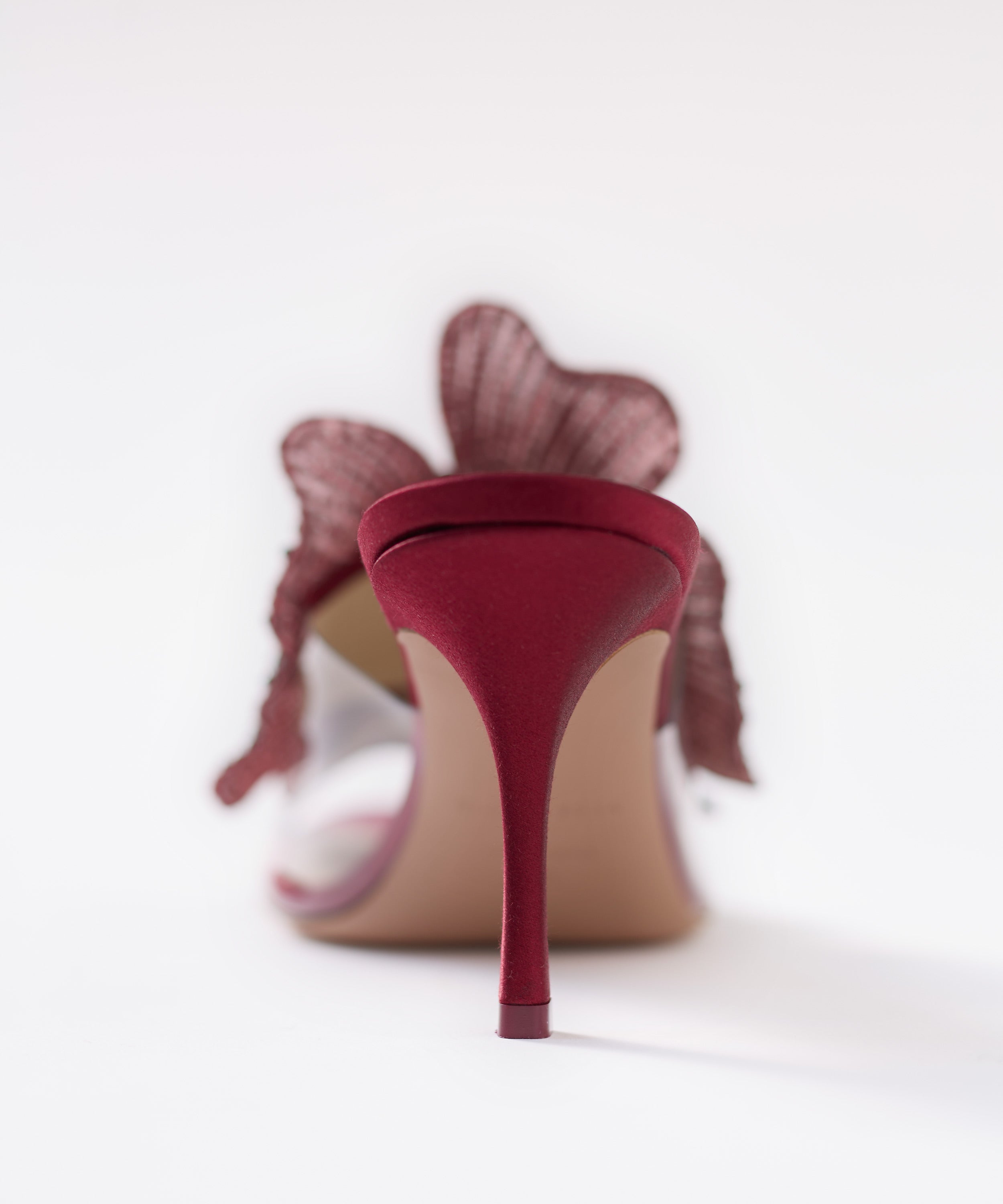Close-up back view of a burgundy 80mm heeled mule, focusing on the thin satin heel on a white background