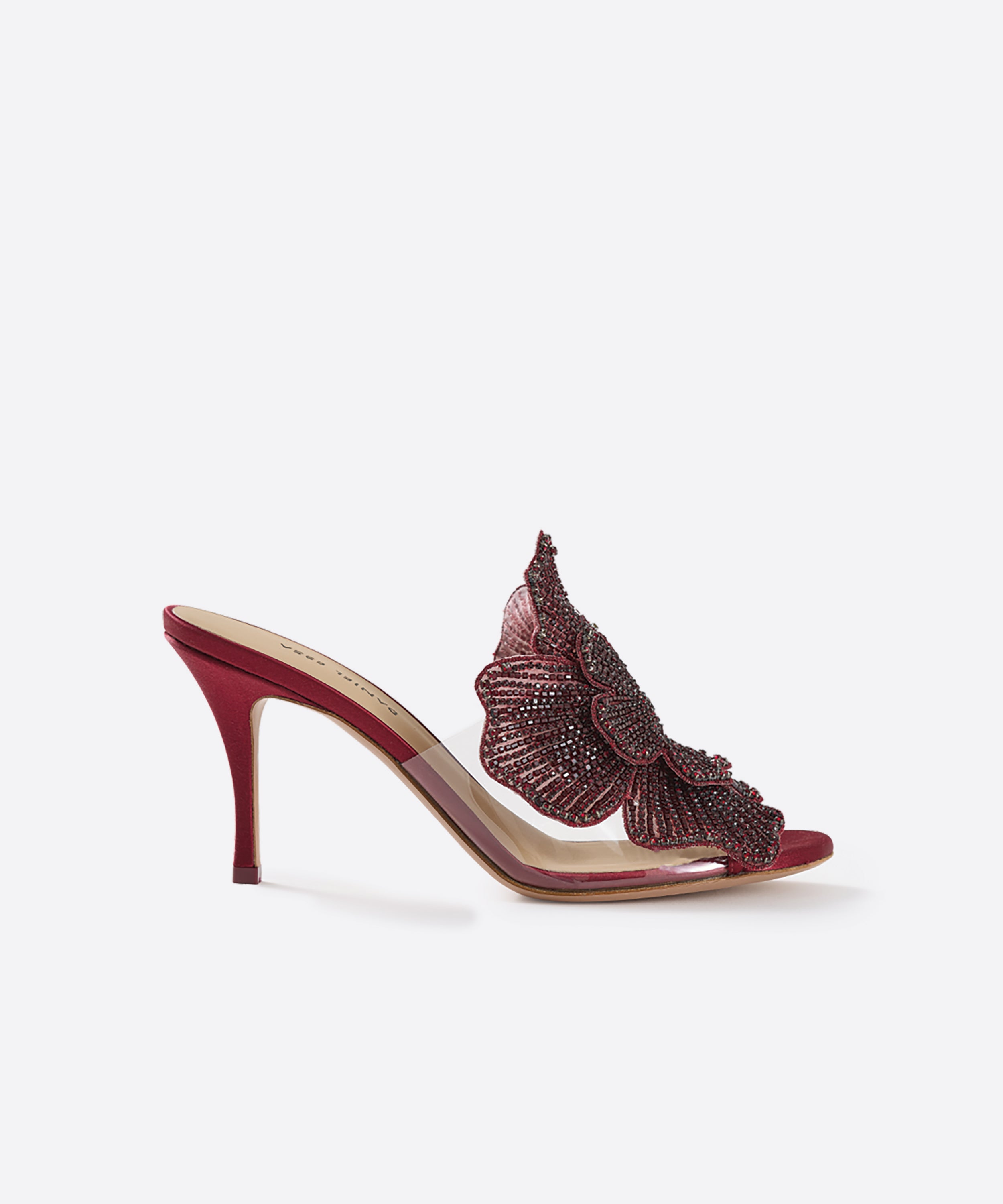Side view of burgundy 80mm heeled mules with a decorative handcrafted crystal flower and a satin heel on a white background