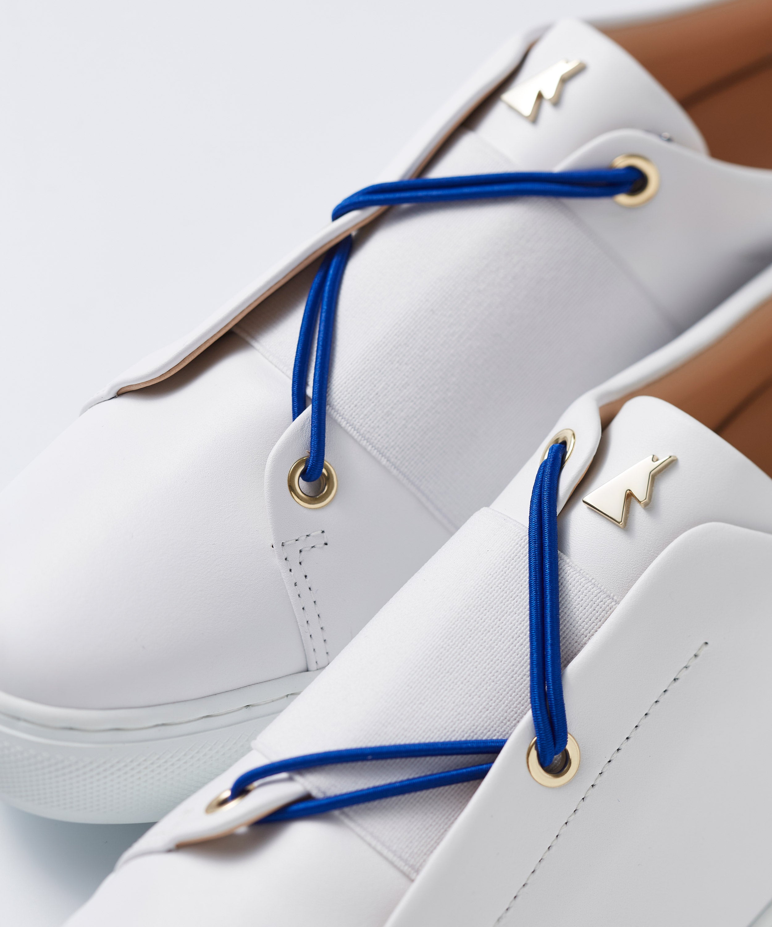 Close-up view of interchangeable electric blue laces for Toi&Moi sneakers, shown on a white premium leather pair